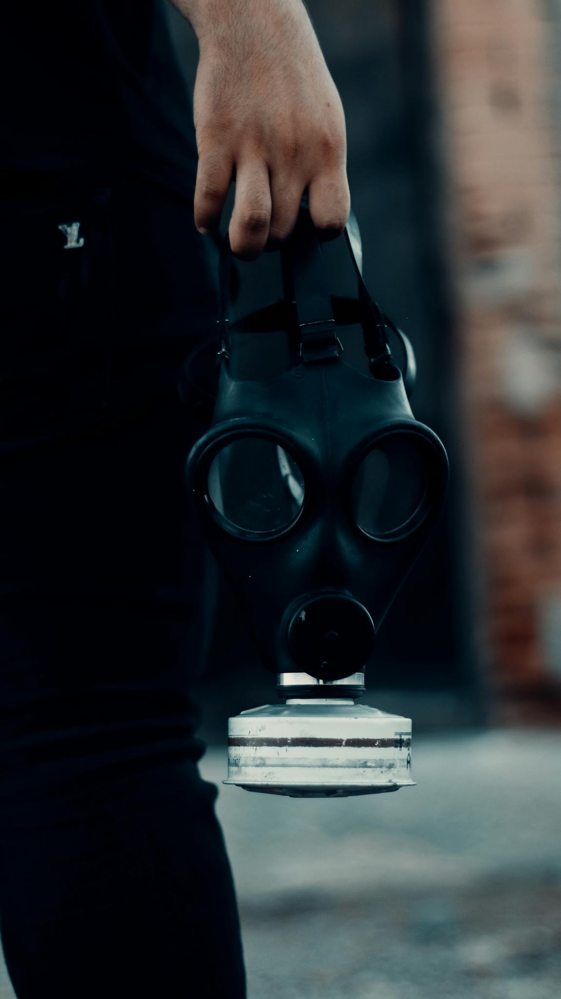 A person holds a gas mask, symbolizing danger and protection in an industrial setting.