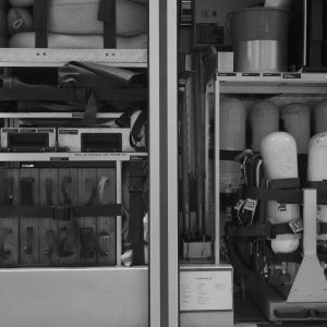 Black and white photo of firetruck equipment and rescue gear neatly organized in compartments.
