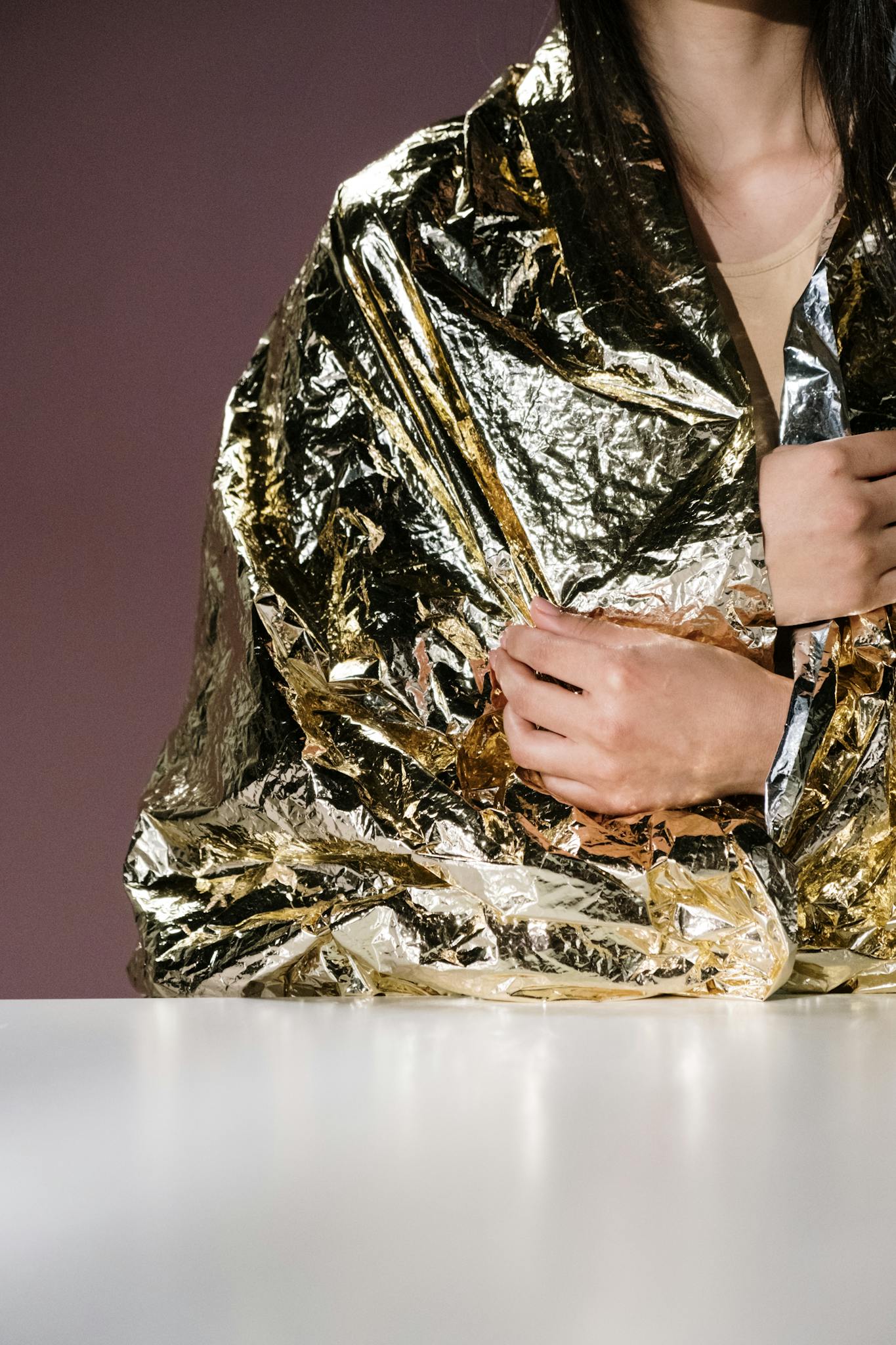 Close-up of a person wrapped in a reflective emergency blanket for warmth and protection.