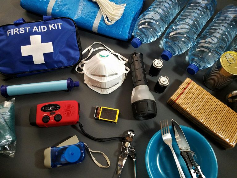 Flat lay of essential emergency survival kit items including first aid and water bottles.