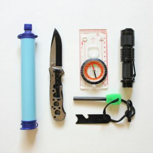 Flatlay of essential survival kit items on a white background